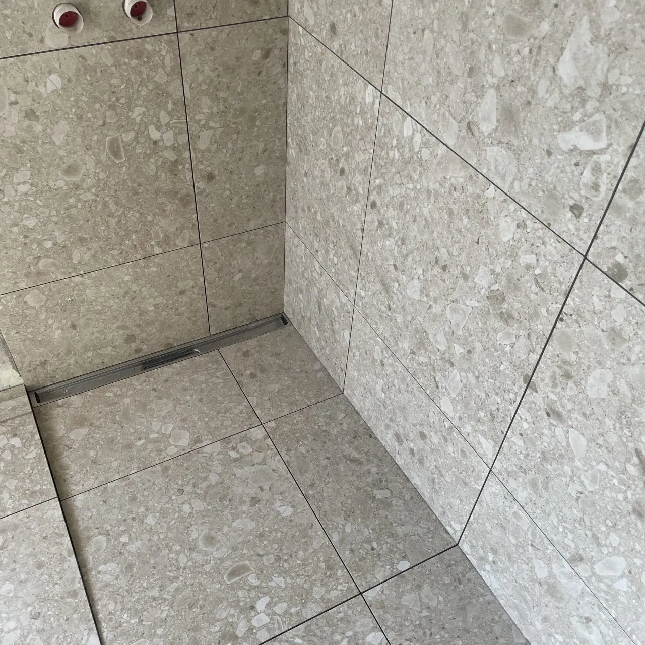 Nyrenoveret bruseniche med terrazzolignende klinker fra gulv til loft