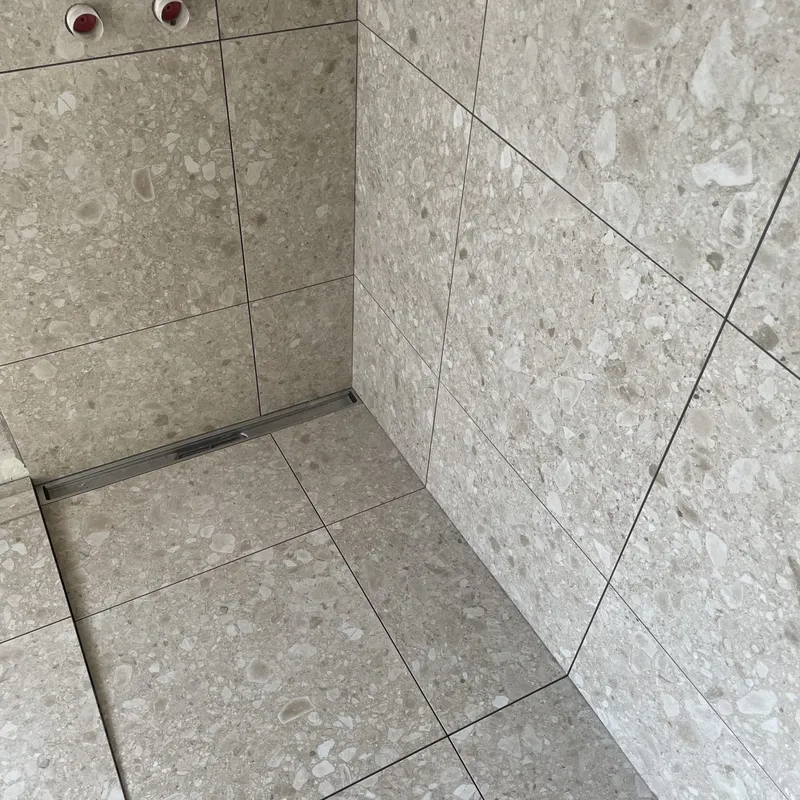 Nyrenoveret bruseniche med terrazzolignende klinker fra gulv til loft