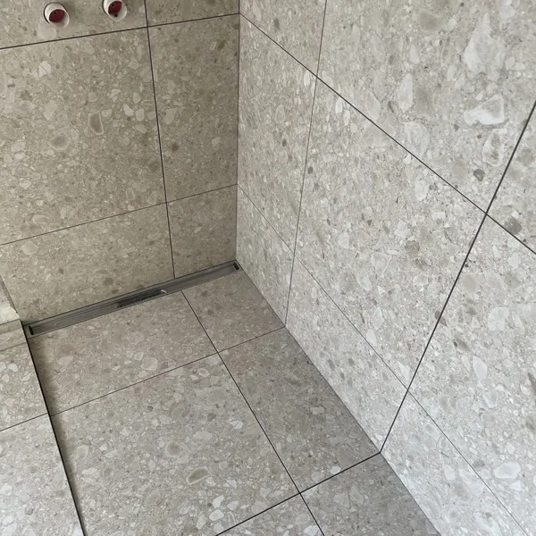 Nyrenoveret bruseniche med terrazzolignende klinker fra gulv til loft